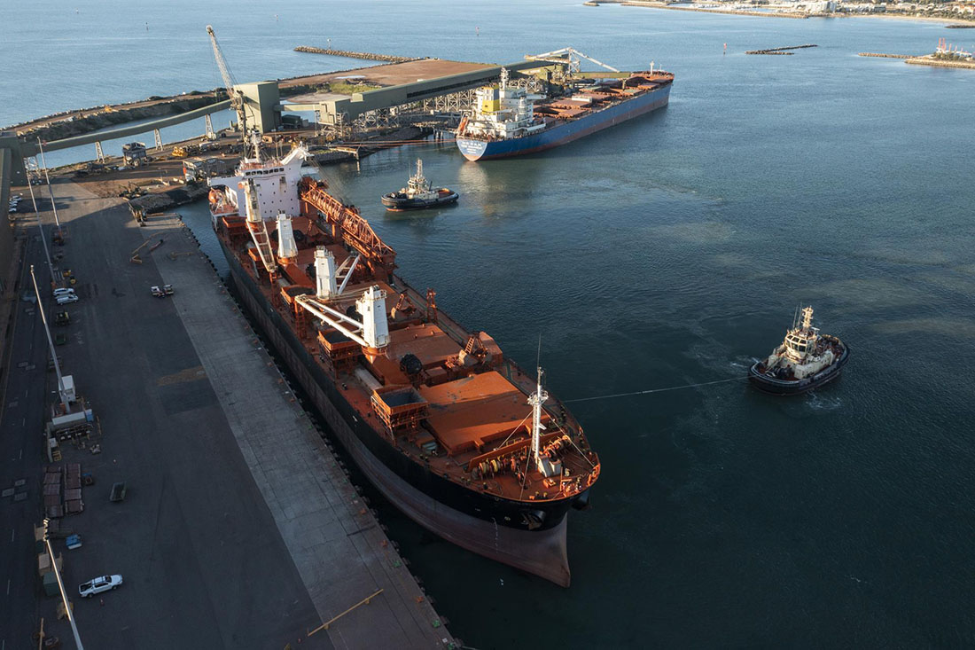 Berth 6 on left with cargo ship and two tugboats.