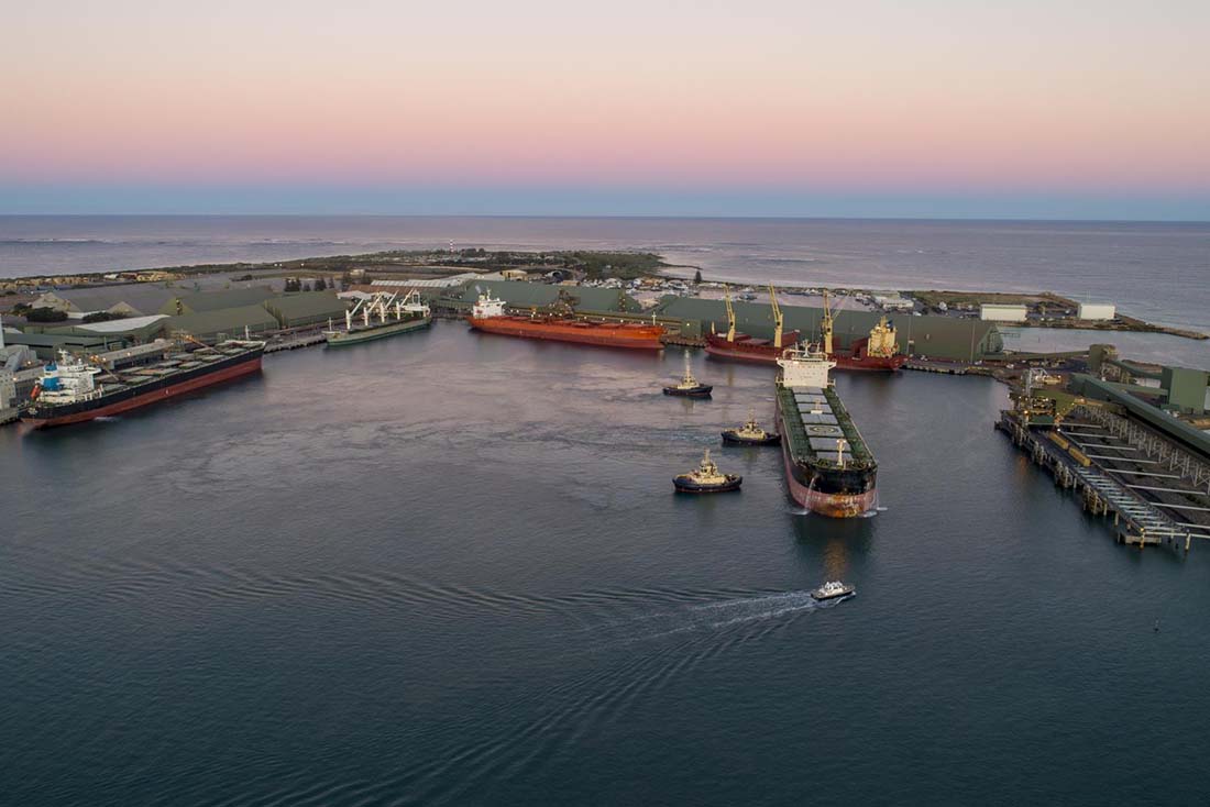 Southwestern view of port at sunrise with 5 ships, 3 tugboats and pilot boat in view.