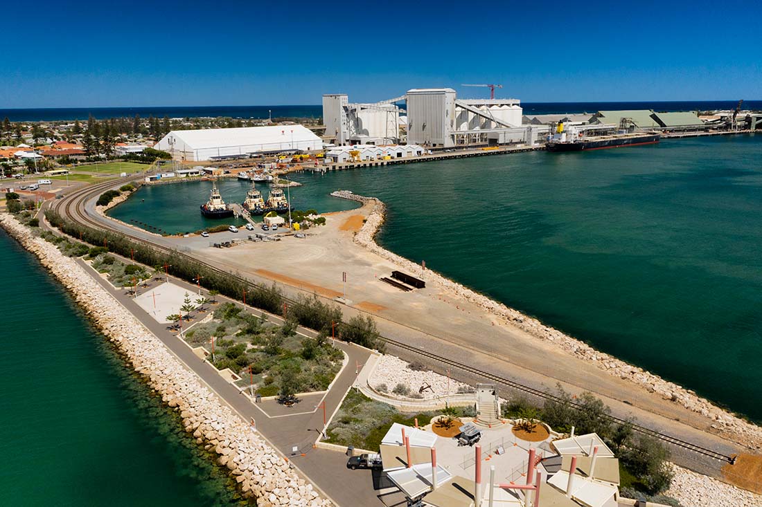 Aerial view of port on clear blue day with 1 ship and 3 tugs