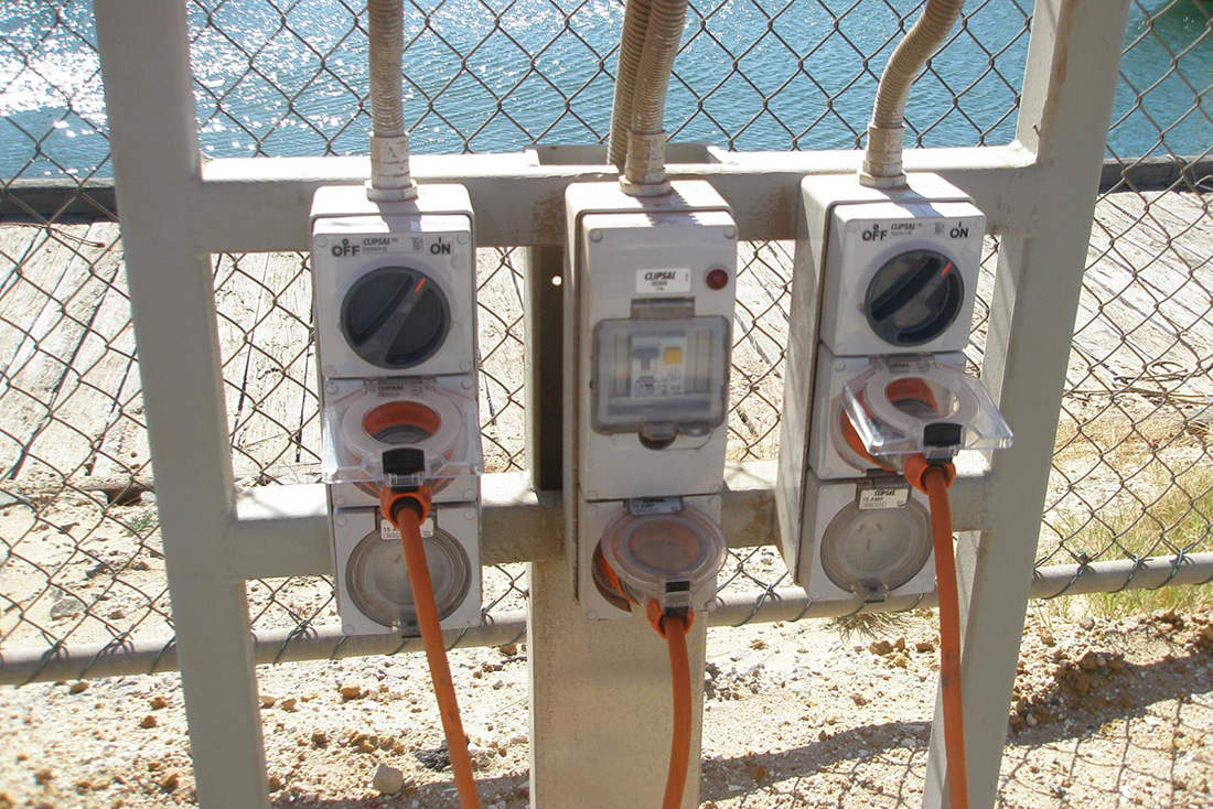 Three electrical outdoor outlets attached to frame in front of chainlink fence