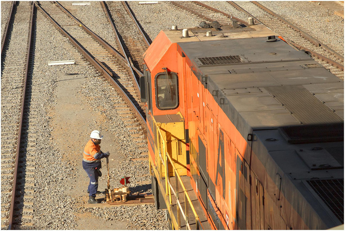 Staff member standing alongside the engine of a train pulling on a lever coming from the ground