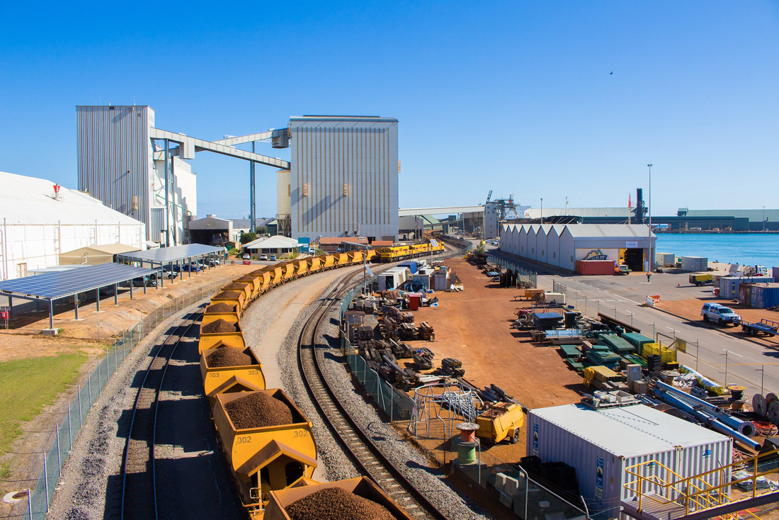 Train cars loaded with grain snaking along rail line in front of the Geraldton port